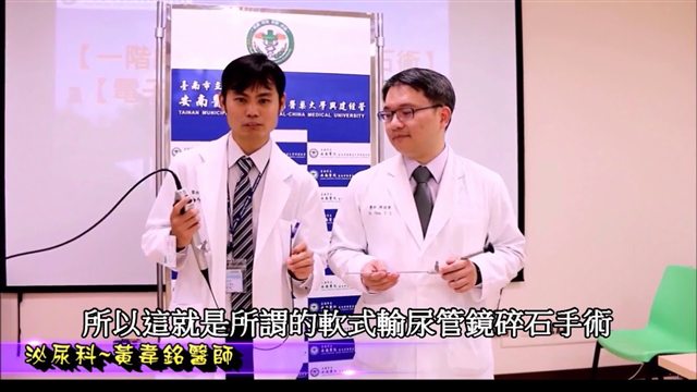 新聞畫面，兩位醫師在記者會上各持一支輸尿管鏡展示，字幕寫著「所以這就是所謂的軟式輸尿管鏡碎石手術」
