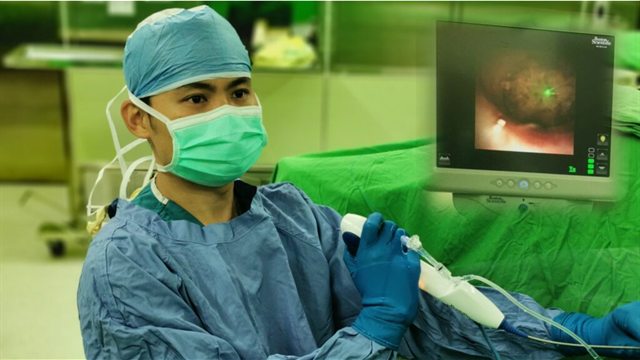手術室內，黃韋銘醫師戴著手術帽與口罩操作軟式輸尿管鏡，右後方螢幕顯示腎臟內部的即時畫面