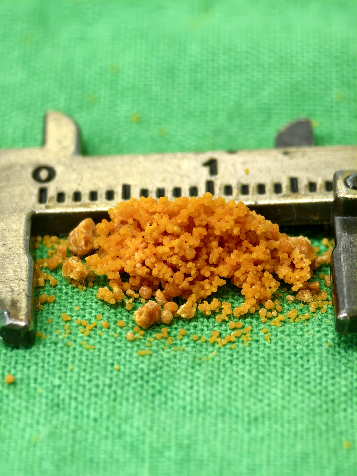 卡尺下一堆鮮橘色的細小顆粒